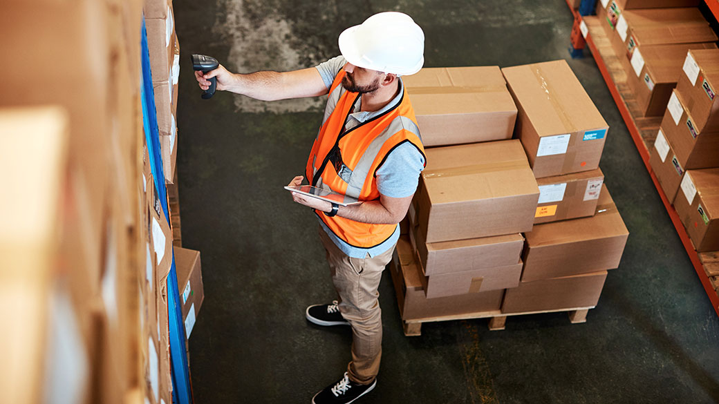 Travailleur masculin scannant le code-barres sur la boîte dans l'entrepôt