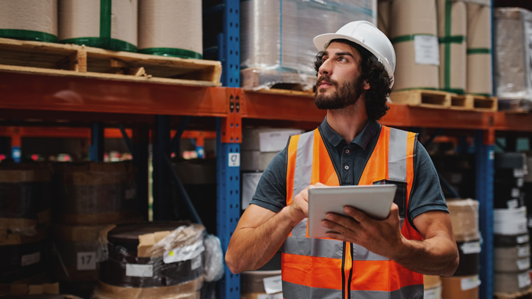 Man wearing safety vest using tablet in warehouse