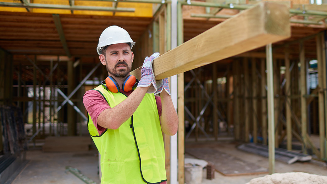 Builder lifting a wooden beam