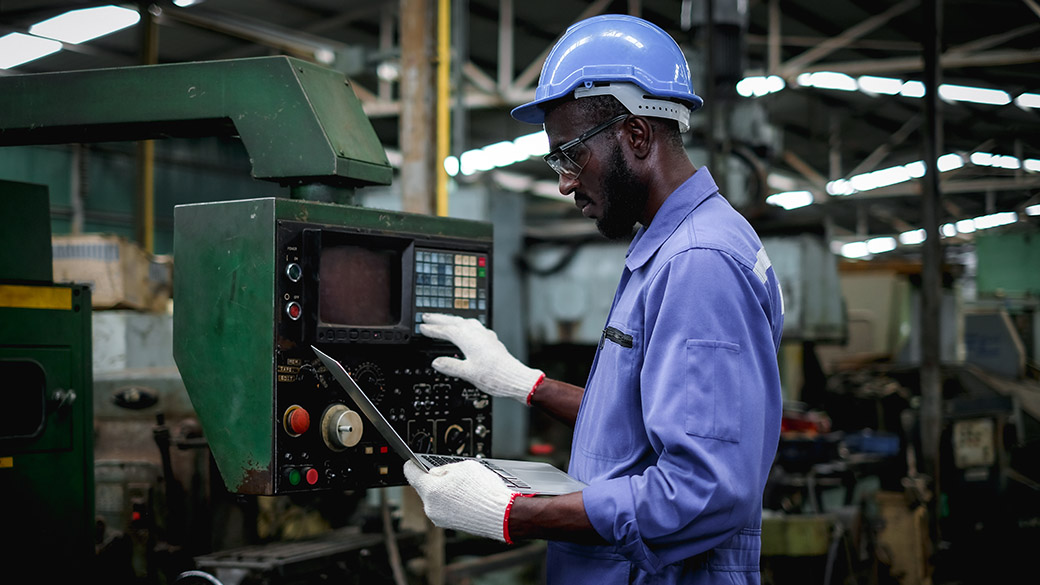 Factory worker using a laptop and testing a machine machine